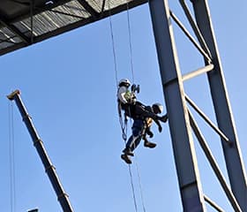 Technician inspecting a rescue tripod for safety compliance